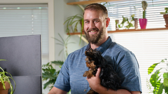 Smiling man with a beard holding a small dog