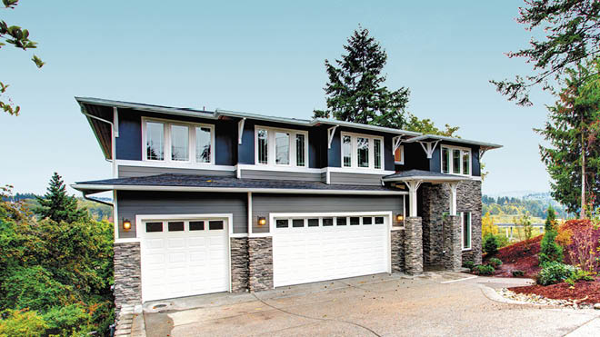 A large blue house with white trim, stone veneer along the lower third and two white garage doors.