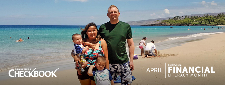 Parents stand smiling with their two young children on a sunny, sandy beach with bright blue water behind them. A white logo on the lower left of the image says: "Consumers' Checkbook." A white logo on the lower right says: "April: National Financial Literacy Month."
