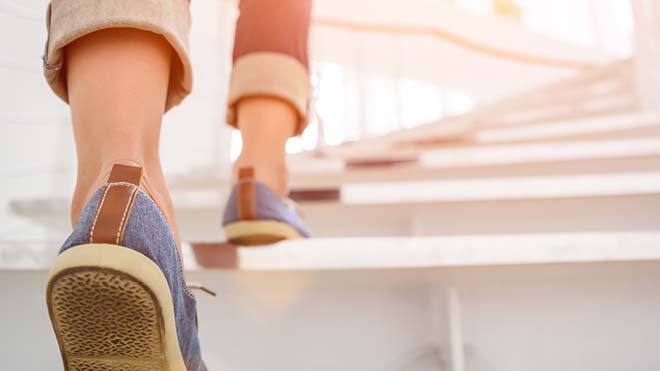 Image is of a person's feet in shoes climbing stairs.