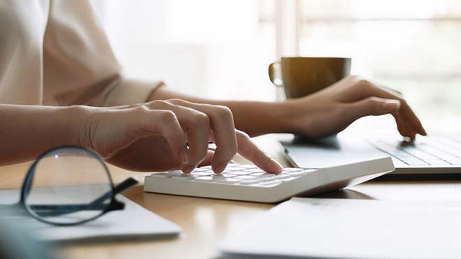 Image is of person sitting at table working on a laptop.