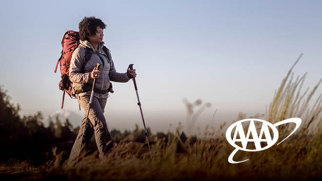 A woman hiking. AAA logo.