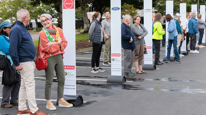 People waiting in a parking lot to test drive electric vehicles.