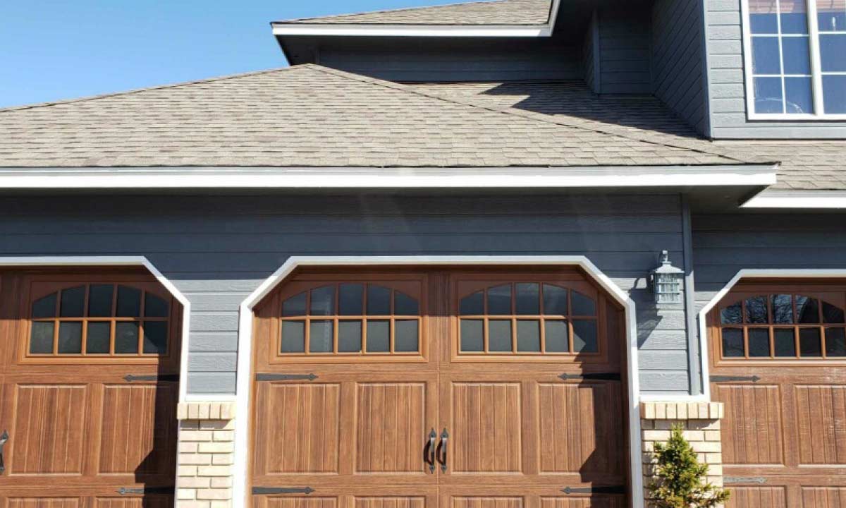 Photo of a house with three wood barn-style garage doors with windows across the top.