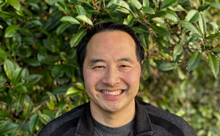 An outdoor headshot of BECU business member Michael Lombard. He is standing in front of greenery.