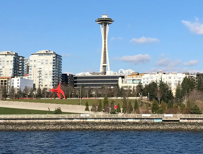 The Seattle waterfront showcases the famous Space Needle, surrounded by modern buildings and a vibrant urban atmosphere.