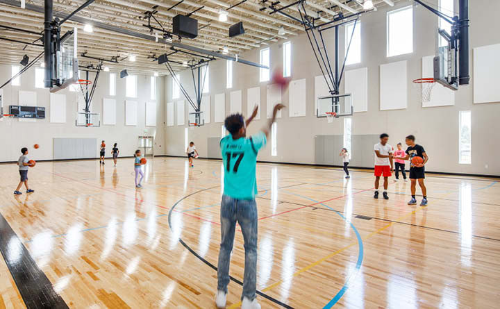 Image shows young people shooting hoops in the Family First Community Center gym.