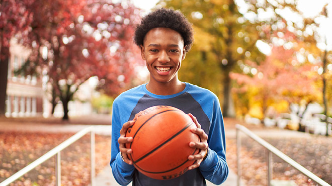 A smiling boy holding a basketball.